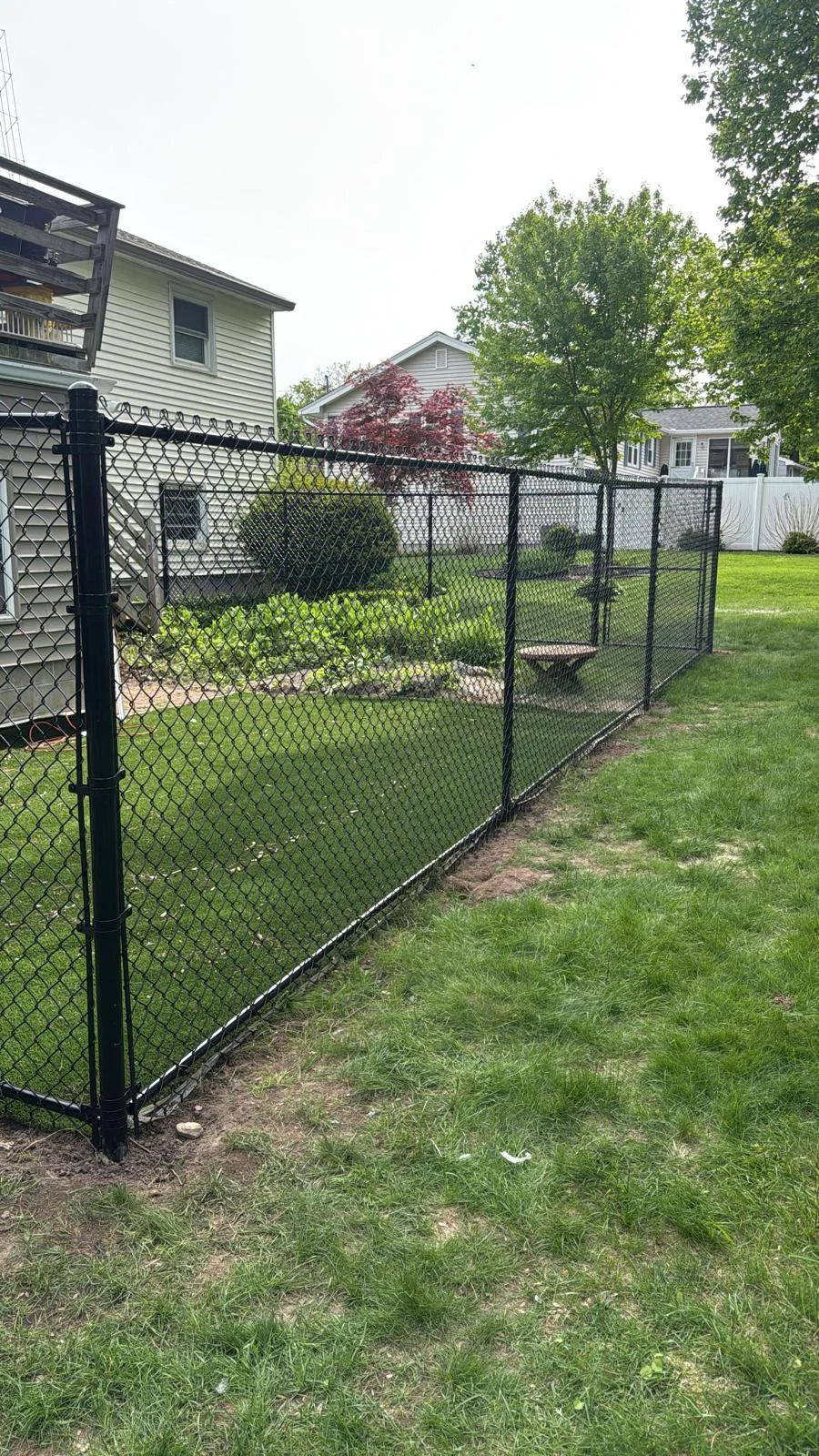 Black chain link fence and gate enclosing a lawn