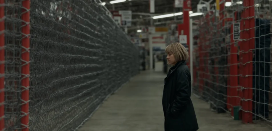 a person standing next to different rolls of chain link fencing in a hardware store aisle in salem nh.
